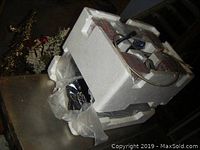 Speakers and subwoofer packed inside white styrofoam packaging, partially visible, with cables wrapped inside plastic bags.