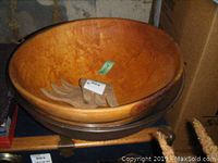 Photo showing the large wooden bowl with two wooden paddles inside, highlighting the wood grain texture and shape of the paddles.
