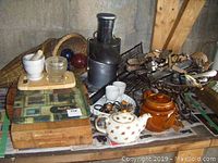 Wide view showing wooden cutting boards, mortar and pestle, glass bowl, wicker baskets, Breville juicer, metal basket with utensils, porcelain teapot and brown ceramic pot.