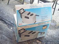 View of two boxed Bravetti professional deep fryers stacked outdoors, showing brand and product