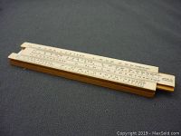 Photo of the entire miniature slide rule showing full length with scales and wooden frame.
