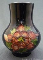 Front side view of the vase showing the cobalt blue background with raised pink Columbine flowers and green leaves.
