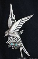 Top view of vintage sterling silver bird brooch showing bird carrying envelope with turquoise stones