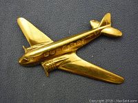Full top view of the brass airplane pin showing shape, windows, propellers and wings.
