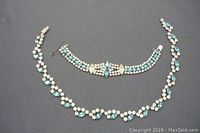 Full view of matching Jay-Flex sterling silver necklace and bracelet set with clear and aqua rhinestones laid on dark surface.