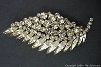 Front view of the Sherman crystal leaf brooch showing clear round and marquise-shaped crystals forming the leaf design on a dark background.