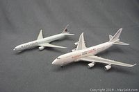 Two 1:500 scale die cast metal airline jet models including Air Canada and Safari Connection on gray background.