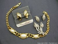 Photo showing the full set of jewelry items on a dark background including earrings, brooch, and bracelet.