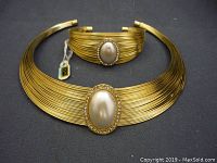 Photo of gold-tone vintage necklace and matching bracelet set laid flat showing oval faux pearl and rhinestone centerpieces