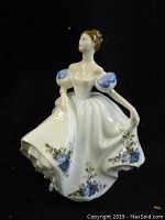 Front view of the porcelain figurine showing the full body and dress with floral patterns.