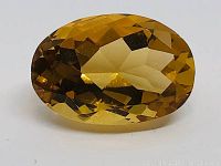 Top-down view showing the oval shape, faceting, and bright golden color of the citrine gemstone.