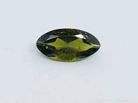 Close-up photo of a marquise cut natural green tourmaline gemstone on a white background, showing the shape and color of the stone.