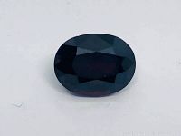 Top view of dark red, oval spinel gemstone showing facets and deep color