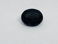 Top view of the oval deep red tourmaline gemstone showing the dark red color and modified mixed cut facets.