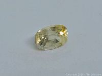 Cushion cut light yellow sapphire gemstone shown from angled side view, highlighting clarity and cut facets.