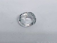 Close-up photo of oval white sapphire gemstone showing modified mixed cut facets and clarity on a white background.