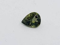 Pear-shaped green tourmaline gemstone on white background showing facets and color.