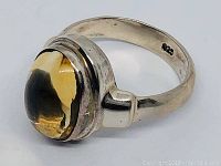 Side angle showing the citrine cabochon stone set in a polished 925 silver band with visible patina.