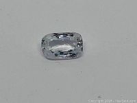 Close-up photo of one transparent white sapphire gemstone with a cushion modified mixed cut on a white background, highlighting the faceted surface and elongated rectangular shape with rounded edges.