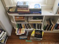 Collection of theology and biblical books on shelves and stacked on the floor near a window.
