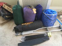 Full lot showing four sleeping bags, Eureka Apex XT tent bag, tent poles, and a pair of crutches.