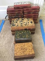 Overview of stacked antique leather bound books, showing various spine designs and marbled covers