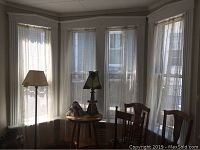 Set of lace curtains hung on windows in a dining room, showing sheerness and style in situ.