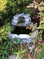 Picture showing the fiberglass outdoor water fountain with artificial rock formation surrounded by plants.