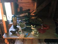 Photo showing multiple bird feeders, ceramic and metal bird decor on a wooden surface inside a barn.