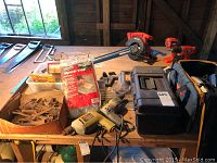 Overview of assorted power tools, saws, hand tools, toolbox and packaged bench vise on wooden table