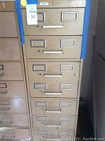 Photo of the beige metal storage cabinet with 8 drawers showing the exterior and drawer handles with label holders.
