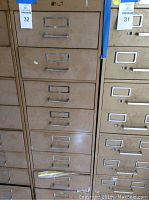 Front view of the metal storage cabinet showing 8 drawers with metal handles and label holders, wear visible on surfaces.