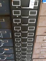 Close-up of 12-drawer metal storage cabinet front showing metal handles and label holders on each drawer.