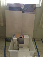 Clear plastic bin containing 8 x 10 inch canvas packs and other smaller canvas pieces in front of large canvases.