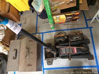 Overall view of the Craftsman hydraulic service jack, metal toolbox, and jack stands on concrete floor with blue tape markings.