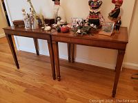 Pair of wooden end tables side by side with various decorative items placed on top (not included). Hardwood floor background.