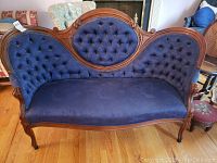Full front view of the Victorian style blue upholstered sofa with tufted back and carved wooden frame.