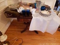 Full view of wooden drop leaf table with various small items placed on top, showing the overall surface and design.