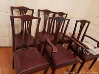 Six dining chairs grouped together in a room showing overall condition and style.