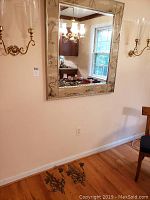 Photo showing wall-mounted rectangular mirror with etched beveled edges and two wall sconces mounted beside it, plus a pair of brass sconces on the floor.
