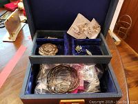 Blue jewelry box containing multiple sterling silver jewelry pieces including bracelets, pins, earrings, and a ring.