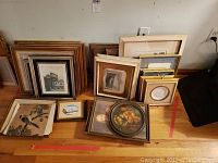 Overall lot of framed artwork organized on floor showing multiple pieces with various frame sizes and subjects.