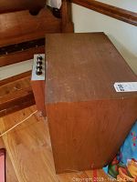 Side view of speaker showing wood veneer cabinet and control panel