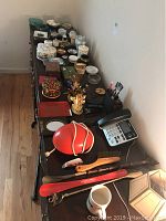 Overview of trinket boxes, ashtrays, bookends, decorative dishes, and small items laid out on a dark wooden table