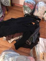 Pile of men's coats on floor, mostly dark wool blend and leather coats visible.