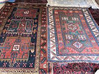 Two overlapping oriental style area rugs side by side on floor, one dark navy background with red geometric medallion, one red field with white stepped border