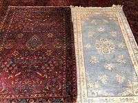 Two area rugs side by side showing overall pattern and size comparison; one red-toned traditional pattern, the other dusty blue with beige floral border and medallion center.