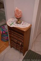 Bookcase with 24 encyclopedia volumes arranged in two rows and a salt lamp on embroidered cloth on top.