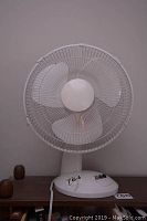Front view of the white Hopeful Electronics table fan showing the circular protective grill and three blades.