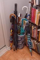 Umbrellas and umbrella stand located in a corner next to a bookshelf